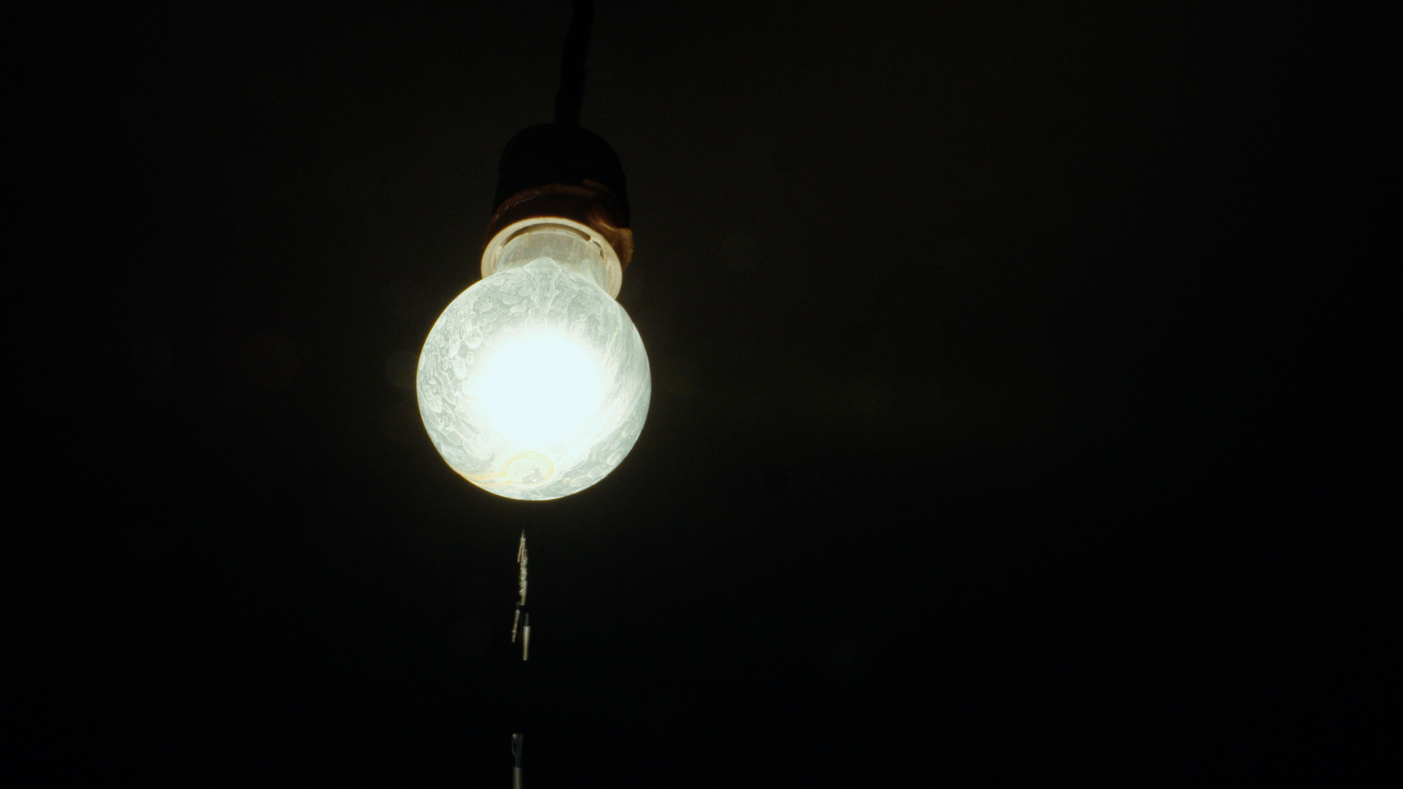 A single light bulb glowing in a dark room