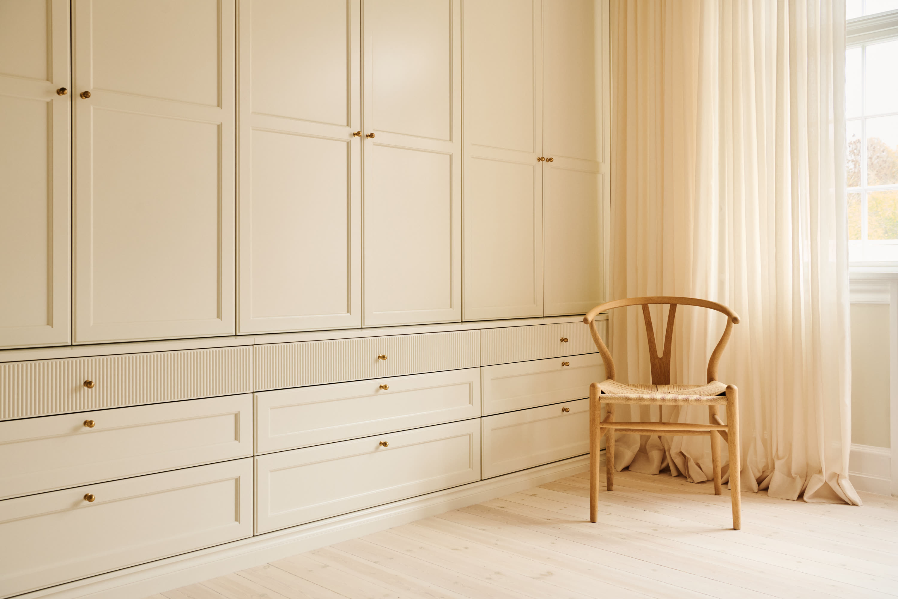The wardrobe with a wishbone chair by the window