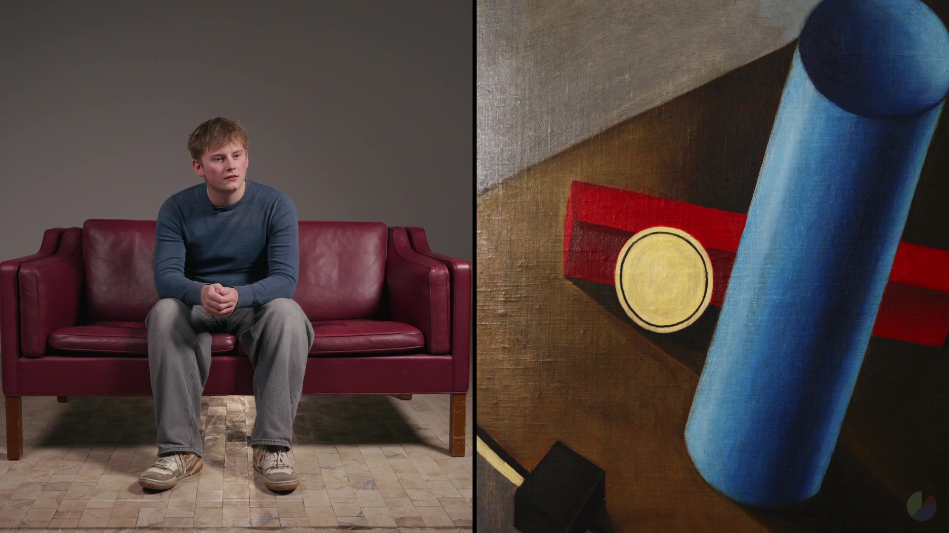 A participant on the red sofa next to a painting with a blue cylinder
