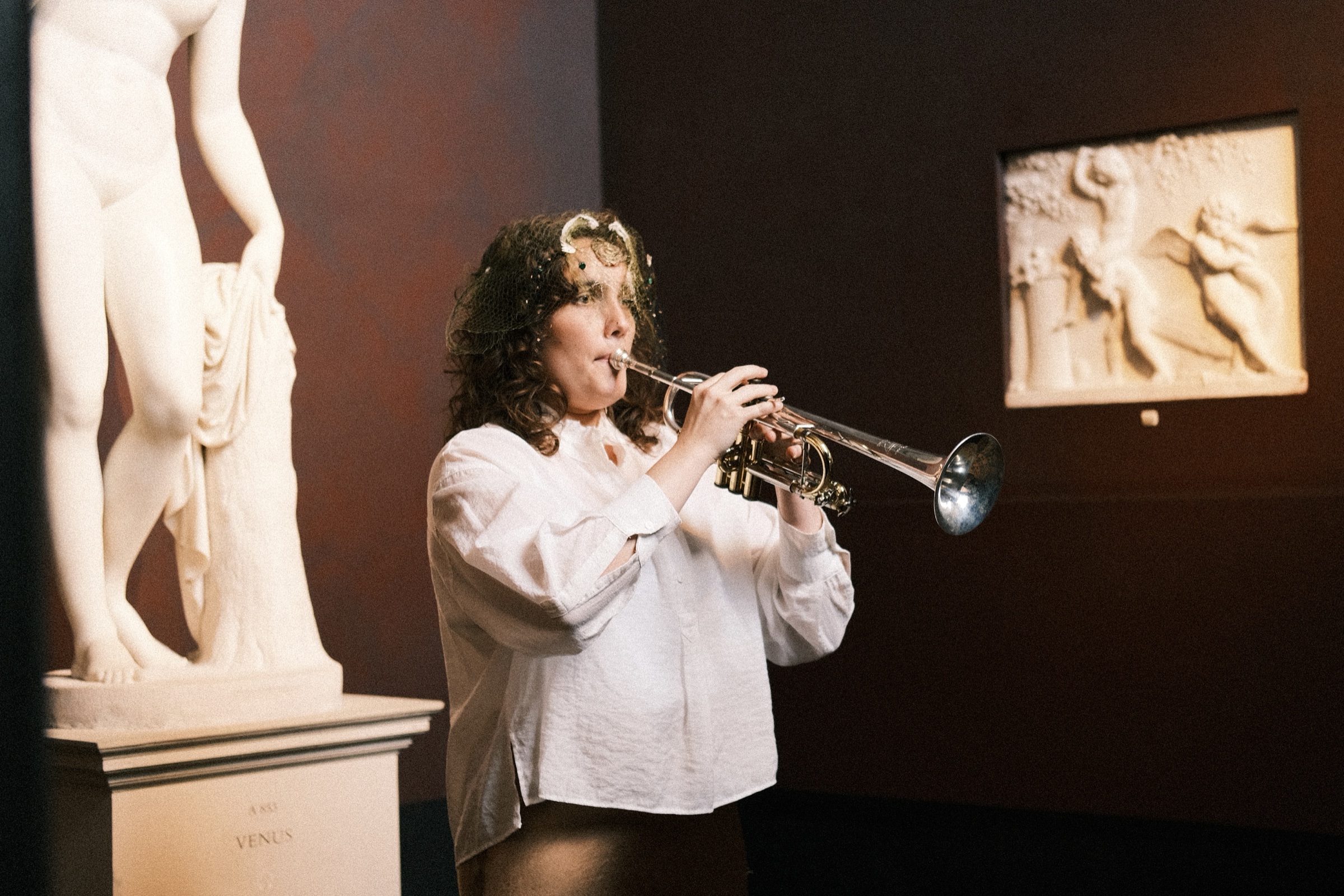 The trumpeter playing beside a marble sculpture