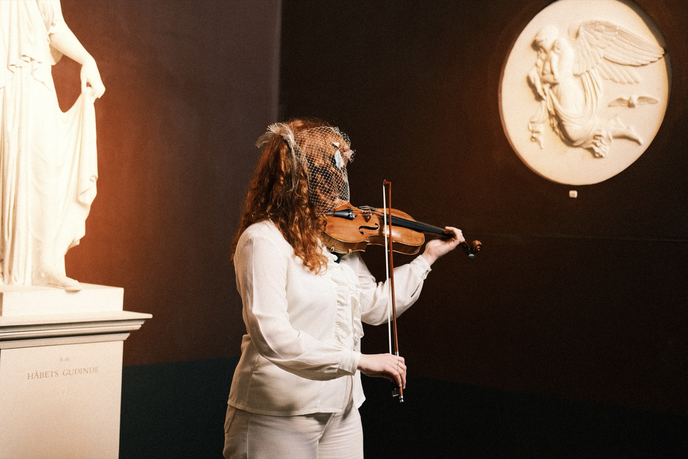 The violinist playing under a marble relief