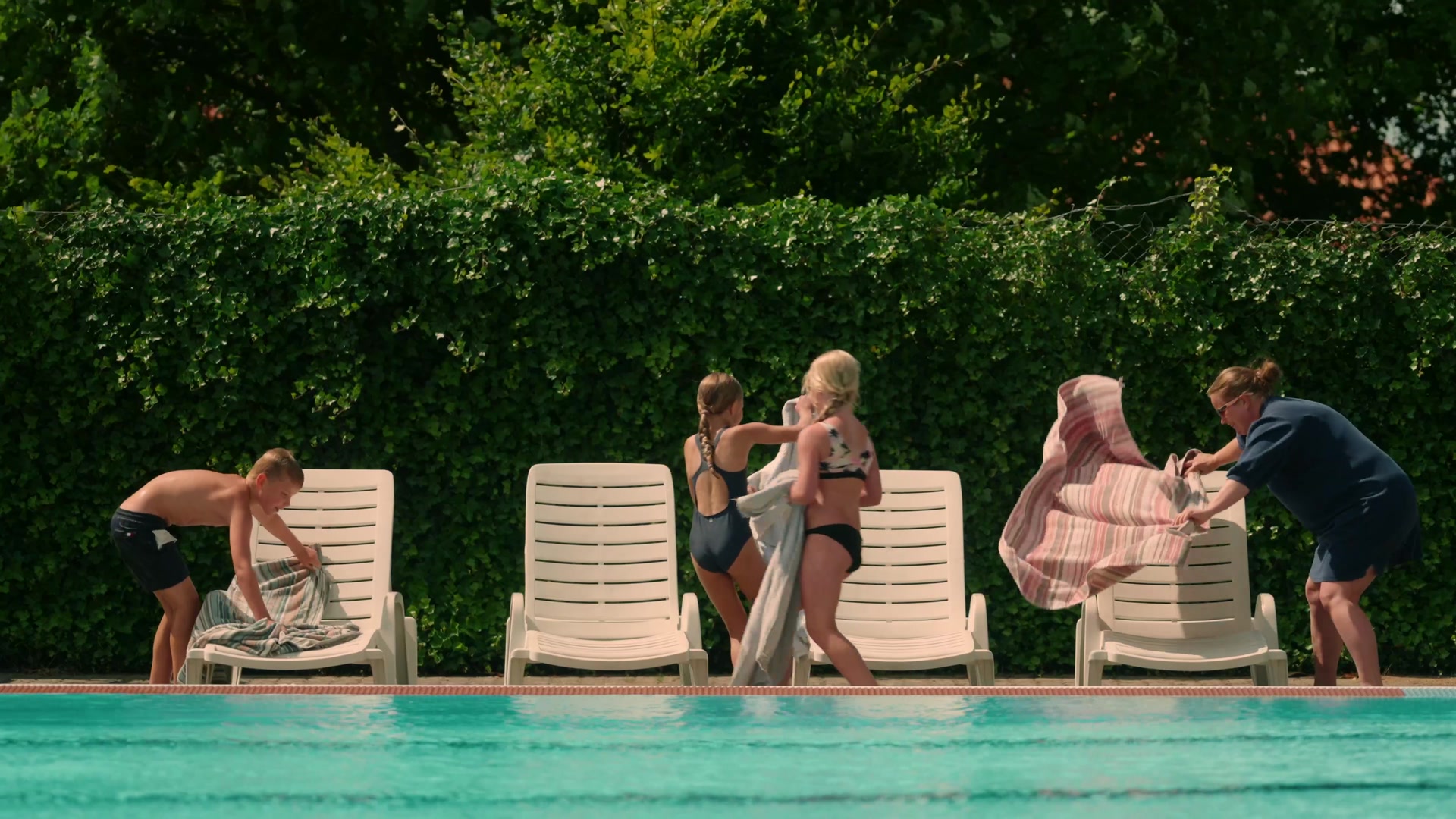 Children laying out towels on the sun loungers by the pool